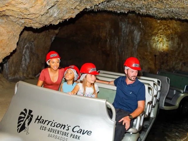 Familie mit Schutzhelmen auf einer Tramfahrt durch Harrison's Cave.