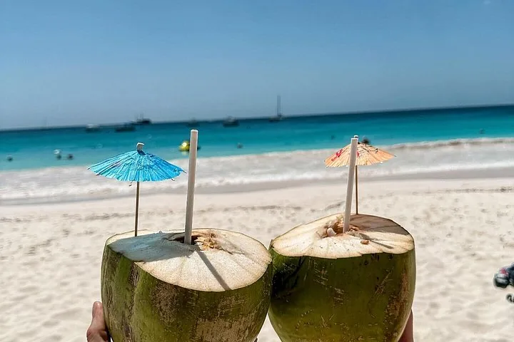 Zwei Kokosnüsse mit Drinks und Schirmchen an einem wunderschönen Sandstrand.